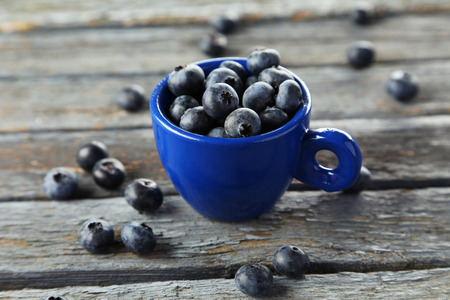 Blueberries in cup on blue wooden backgroundの写真素材