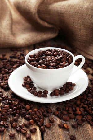 Cup full of coffee beans on brown wooden backgroundの写真素材