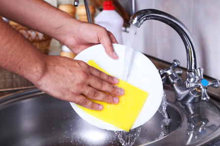 Male hand with sponge washing dish の写真素材