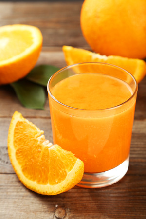 Orange fruit and glass of juice on brown wooden backgroundの写真素材