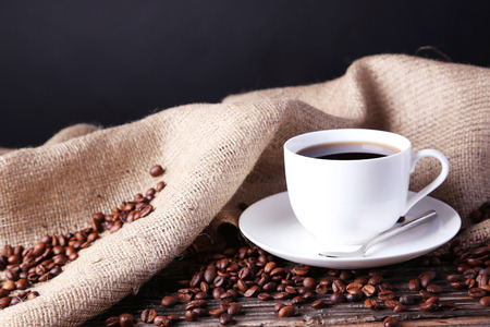 Cup of coffee with coffee beans on brown wooden backgroundの写真素材