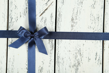 Blue ribbon with bow on white wooden backgroundの写真素材