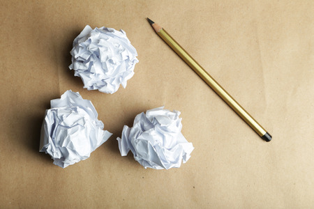 Crumpled paper balls with pencil on brown backgroundの写真素材