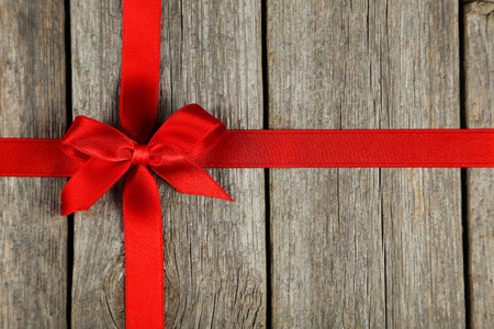 Red ribbon with bow on grey wooden backgroundの写真素材