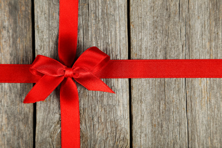 Red ribbon with bow on grey wooden backgroundの写真素材
