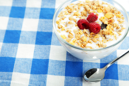 Muesli with yogurt and raspberries in a bowl on napkinの写真素材