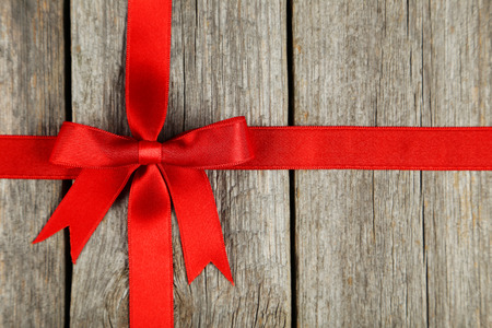 Red ribbon with bow on grey wooden backgroundの写真素材