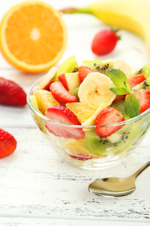 Fresh fruit salad in bowl on white wooden backgroundの写真素材