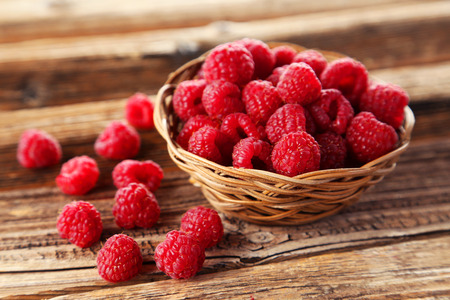 Raspberries in basket on brown wooden backgroundの写真素材