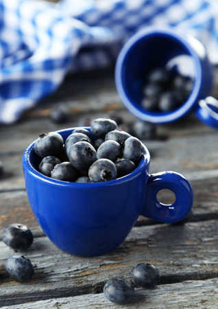 Blueberries in cup on blue wooden backgroundの写真素材