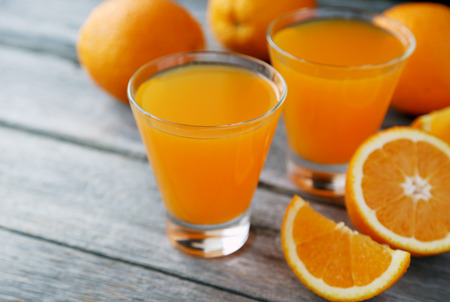 Glass of fresh orange juice on grey wooden backgroundの写真素材