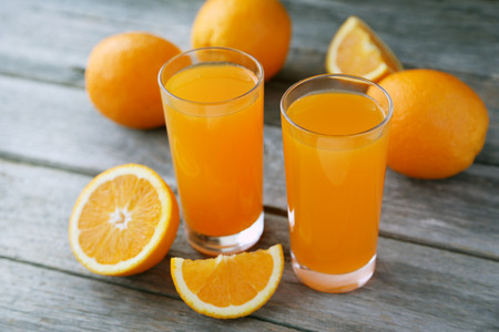 Glass of fresh orange juice on grey wooden backgroundの写真素材