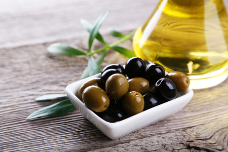 Green and black olives in bowl on grey wooden backgroundの写真素材