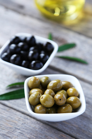 Green and black olives in bowl on grey wooden backgroundの写真素材