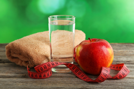 Red apple with measuring tape and glass of water on grey wooden backgroundの写真素材