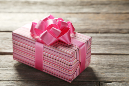 Gift box with pink bow on grey wooden backgroundの写真素材