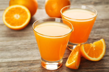 Glass of fresh orange juice on grey wooden backgroundの写真素材