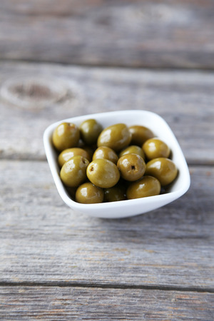 Green olives in bowl on grey wooden backgroundの写真素材