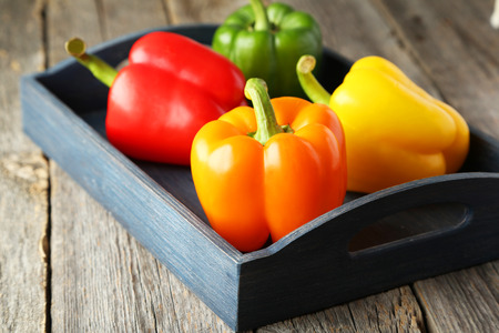 Four fresh pepper in blue tray on grey wooden backgroundの写真素材