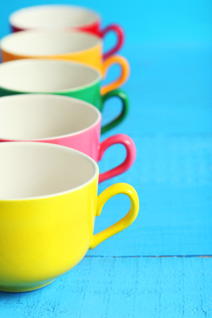 Colorful cups on blue wooden backgroundの写真素材