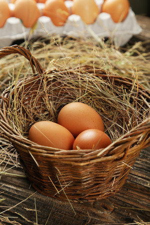 Eggs in basket on brown wooden backgroundの写真素材