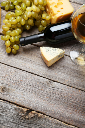 Glass of white wine, cheeses and grapes on grey wooden backgroundの写真素材