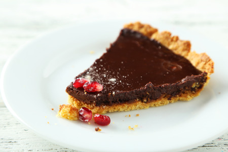 Homemade chocolate tart with pomegranate on white wooden backgroundの写真素材