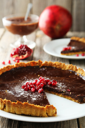 Homemade chocolate tart with pomegranate on grey wooden backgroundの写真素材