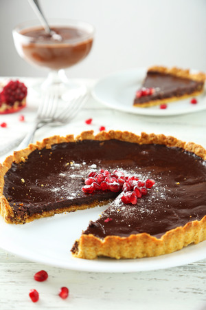 Homemade chocolate tart with pomegranate on white wooden backgroundの写真素材