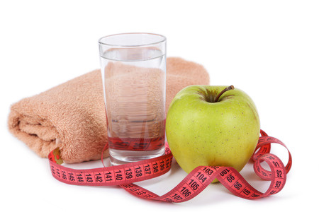 Green apple with measuring tape and glass of water isolated on whiteの写真素材