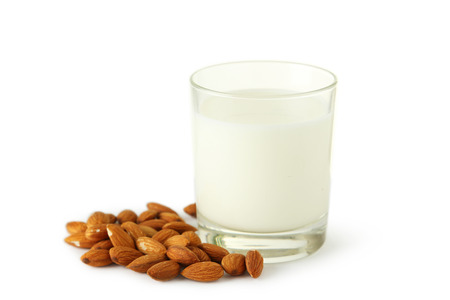 Glass of milk with almonds isolated on whiteの写真素材
