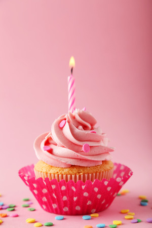 Tasty cupcake with candle on pink backgroundの写真素材