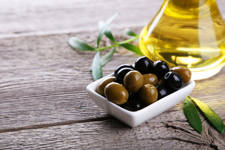 Green and black olives in bowl on grey wooden backgroundの写真素材