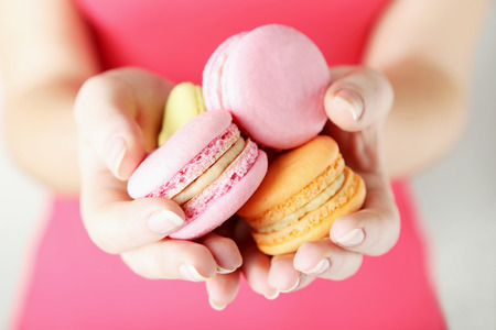 Female hands holding colorful french macaronsの写真素材