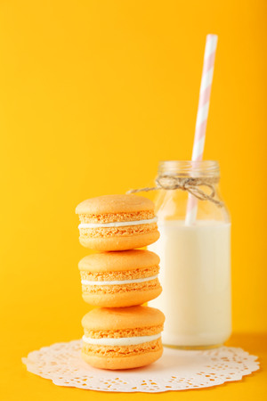 French macarons with bottle of milk on orange backgroundの写真素材