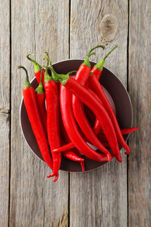 Red chili pepper on plate on grey wooden backgroundの写真素材