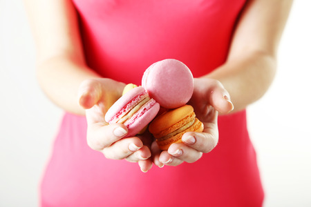 Female hands holding colorful french macaronsの写真素材