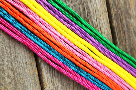 Colorful ropes on grey wooden background
