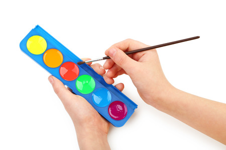 Child hand dips the brush in watercolorの写真素材