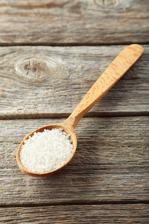 Sea salt in wooden spoon on grey wooden backgroundの写真素材
