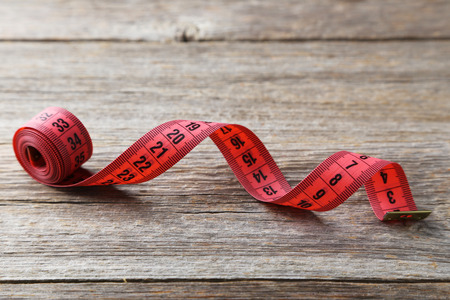 Measuring tape on grey wooden background