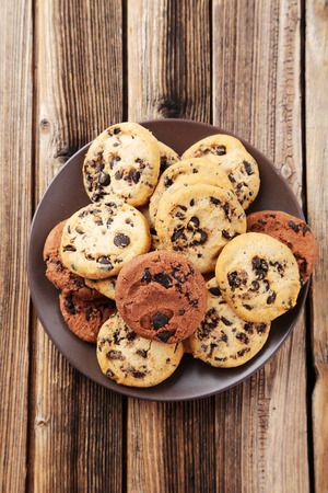 Chocolate chip cookies on plate on brown wooden backgroundの写真素材