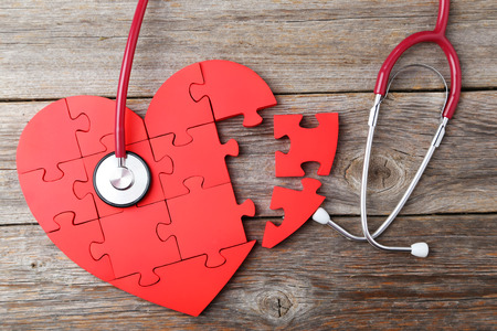 Red puzzle heart with stethoscope on grey wooden backgroundの写真素材