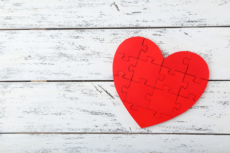 Red puzzle heart on white wooden backgroundの写真素材