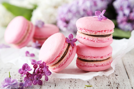 French pink macarons with lilac flowers on white wooden backgroundの写真素材