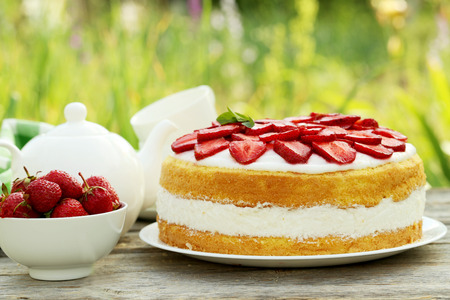 Sweet cake with strawberries on plate on grey wooden backgroundの写真素材