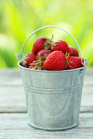 Strawberries berry in bucket on grey wooden backgroundの写真素材