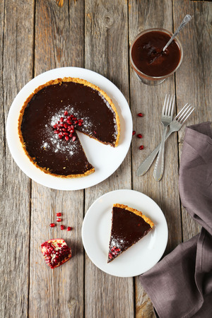 Homemade chocolate tart with pomegranate on grey wooden backgroundの写真素材