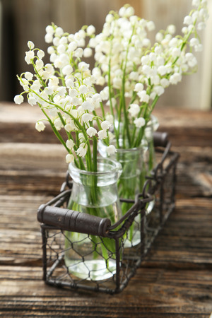 Lily of the Valley in bottles on brown wooden backgroundの写真素材