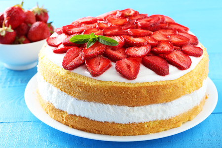 Sweet cake with strawberries on plate on blue wooden backgroundの写真素材